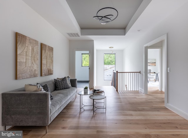 living room featuring a tray ceiling and light hardwood / wood-style floors