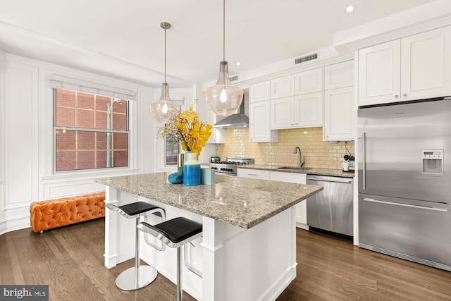 kitchen featuring a center island, dark wood-type flooring, white cabinetry, stainless steel appliances, and decorative light fixtures