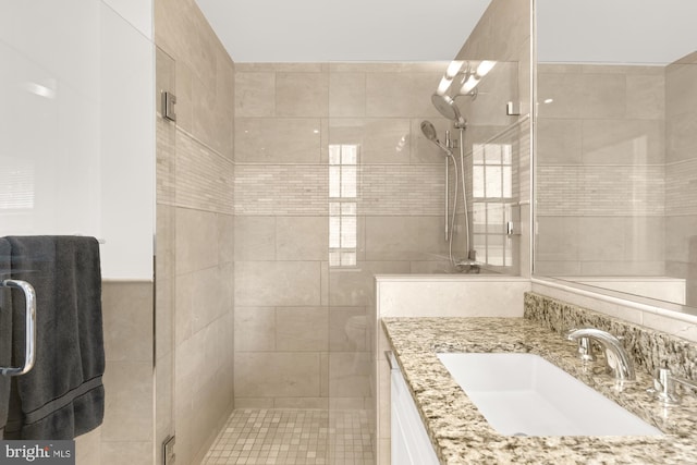 bathroom featuring tile walls, a shower with shower door, and vanity