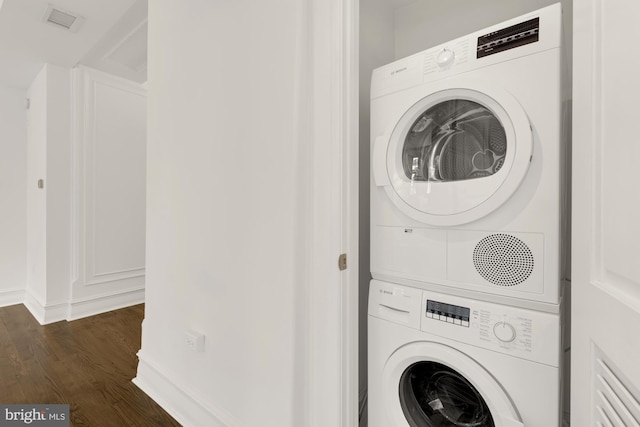 clothes washing area with stacked washer and clothes dryer and dark wood-type flooring