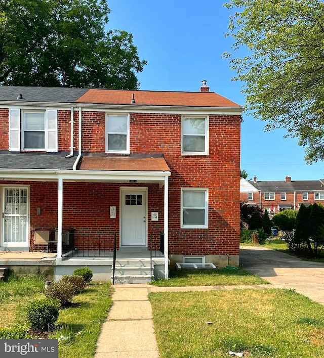 townhome / multi-family property with a porch and a front lawn