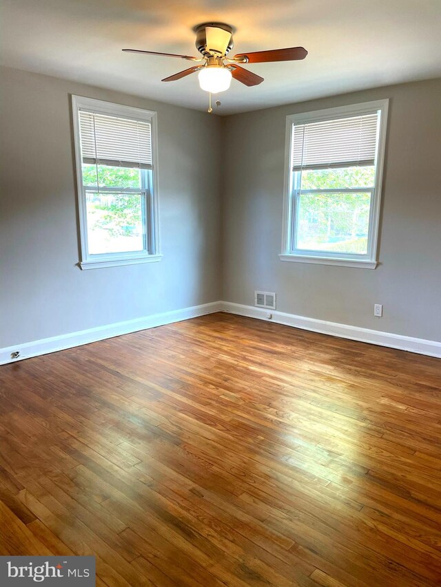 empty room featuring wood-type flooring, ceiling fan, and a wealth of natural light