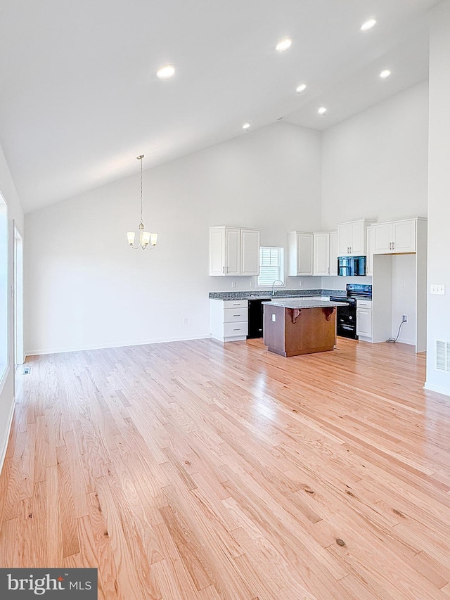 kitchen with black appliances, white cabinets, and open floor plan