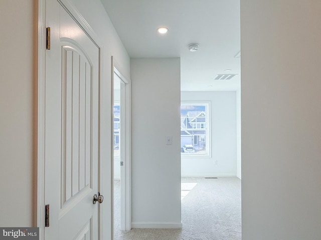 hallway featuring visible vents, carpet flooring, and baseboards