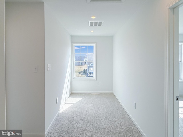 hall with visible vents, carpet floors, and baseboards