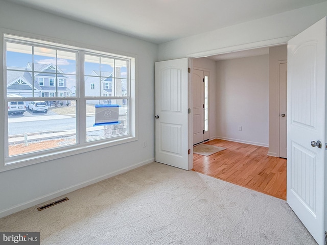 entryway featuring visible vents, light colored carpet, and baseboards