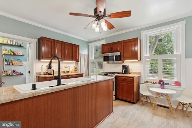 kitchen with ceiling fan, a wealth of natural light, stainless steel appliances, and ornamental molding