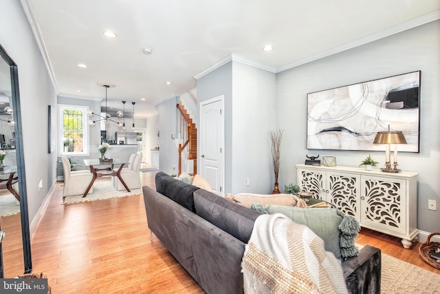 living room with ornamental molding, light hardwood / wood-style floors, and a notable chandelier