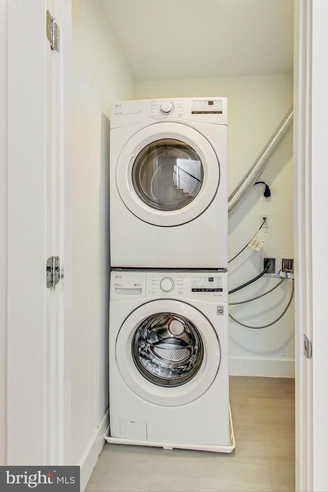 laundry room with light hardwood / wood-style flooring and stacked washer / dryer