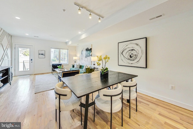 dining space with light hardwood / wood-style flooring and rail lighting