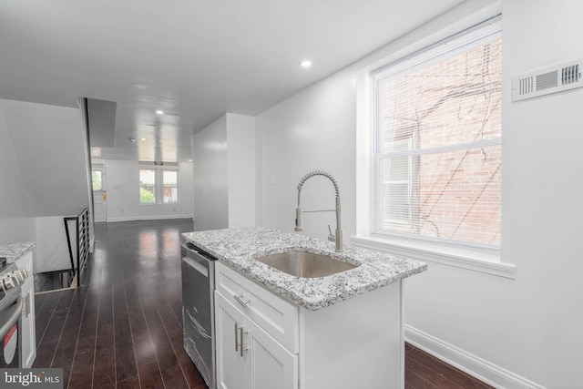 kitchen with light stone countertops, dark hardwood / wood-style flooring, white cabinetry, sink, and a center island with sink