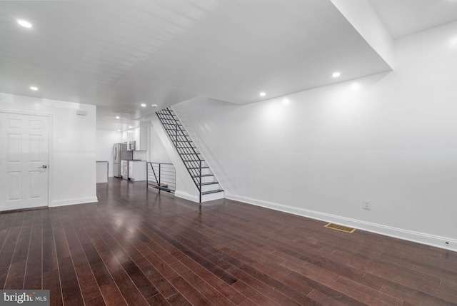 basement featuring dark hardwood / wood-style flooring and stainless steel refrigerator