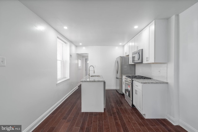 kitchen with backsplash, stainless steel appliances, light stone counters, dark hardwood / wood-style floors, and white cabinets