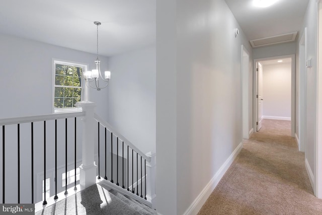 hallway featuring a notable chandelier and light colored carpet