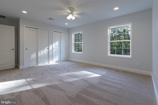 unfurnished bedroom featuring multiple windows, ceiling fan, and light colored carpet