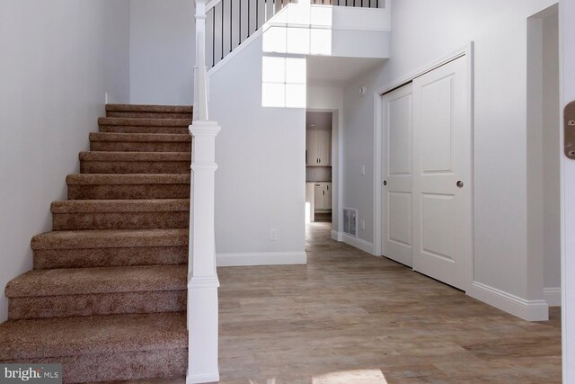 stairway featuring wood-type flooring and a towering ceiling