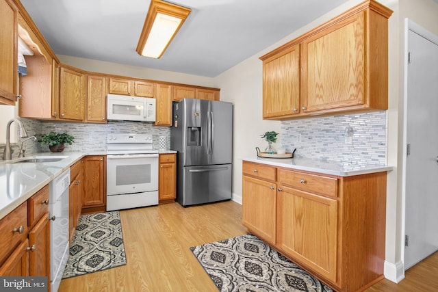 kitchen with white appliances, light hardwood / wood-style floors, tasteful backsplash, and sink