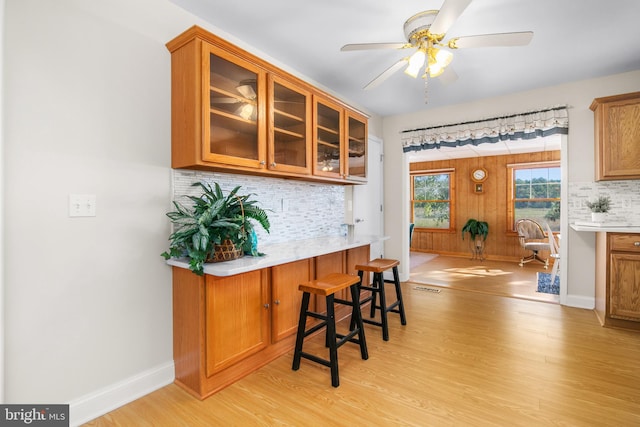 kitchen featuring backsplash, a breakfast bar, light hardwood / wood-style floors, and ceiling fan