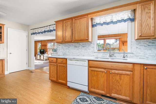 kitchen with sink, decorative backsplash, dishwasher, and light wood-type flooring