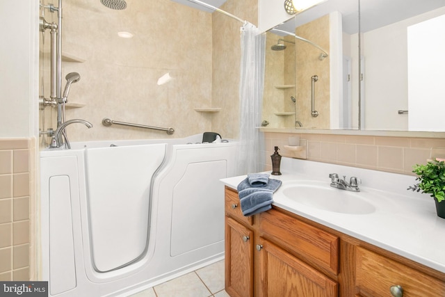 bathroom featuring vanity, tile patterned floors, tiled shower / bath, and tile walls