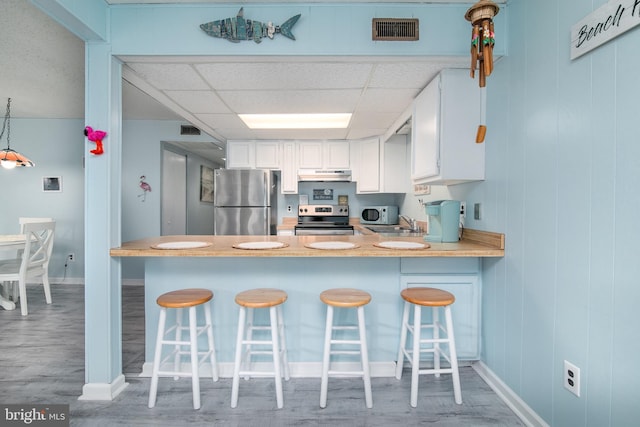 kitchen featuring a kitchen bar, light hardwood / wood-style flooring, stainless steel appliances, and kitchen peninsula