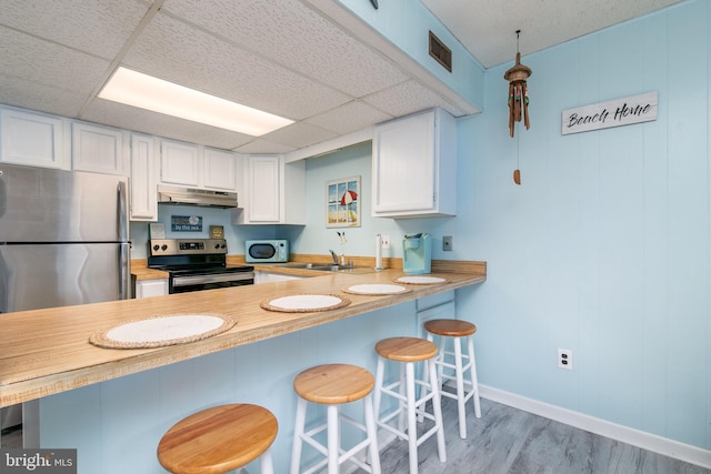 kitchen featuring appliances with stainless steel finishes, light wood-type flooring, kitchen peninsula, and white cabinetry