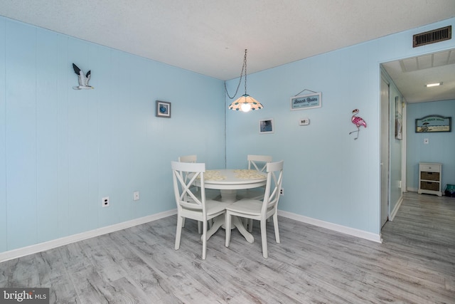 dining room with a textured ceiling and light hardwood / wood-style floors