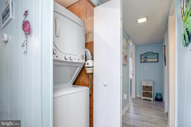 715 142nd St Unit 42304, Ocean City, MD 21842 - clothes washing area with a textured ceiling, light wood-style flooring, baseboards, laundry area, and stacked washing maching and dryer