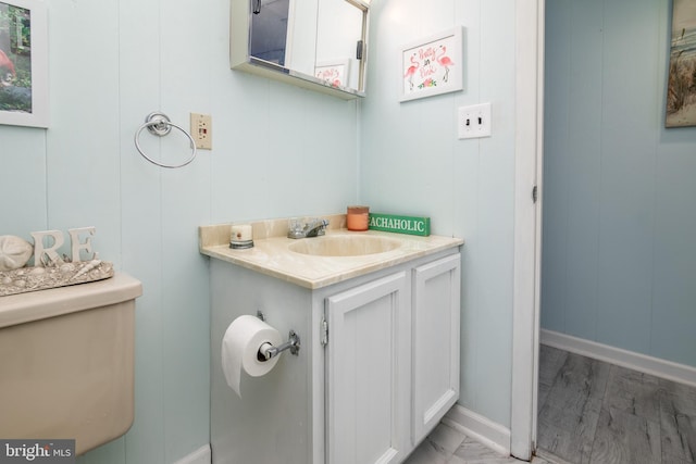 bathroom featuring wooden walls, hardwood / wood-style flooring, vanity, and toilet