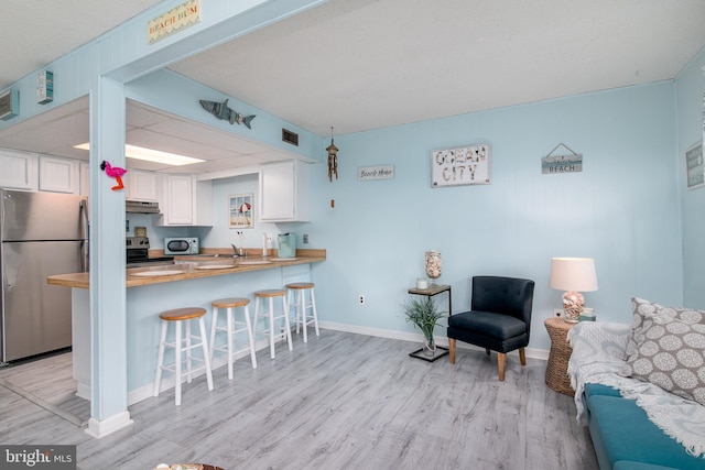 715 142nd St Unit 42304, Ocean City, MD 21842 - kitchen featuring open floor plan, a kitchen breakfast bar, stainless steel appliances, under cabinet range hood, and white cabinets