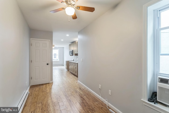 hallway with light hardwood / wood-style floors, baseboard heating, and plenty of natural light