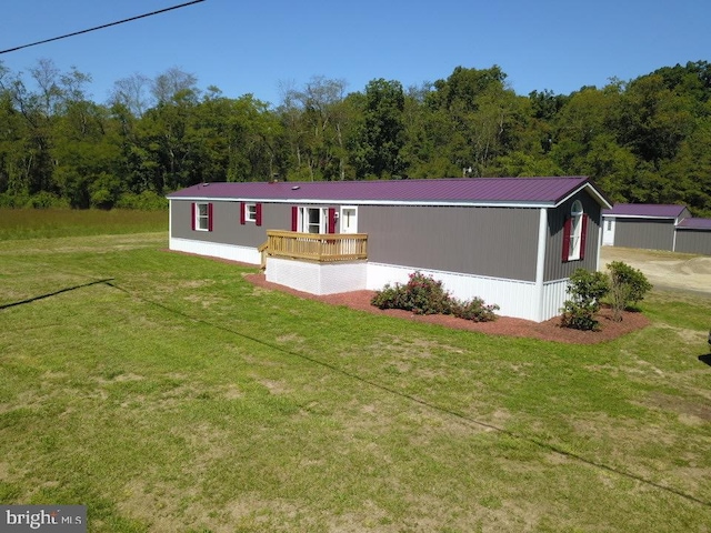 manufactured / mobile home featuring a wooden deck and a front lawn