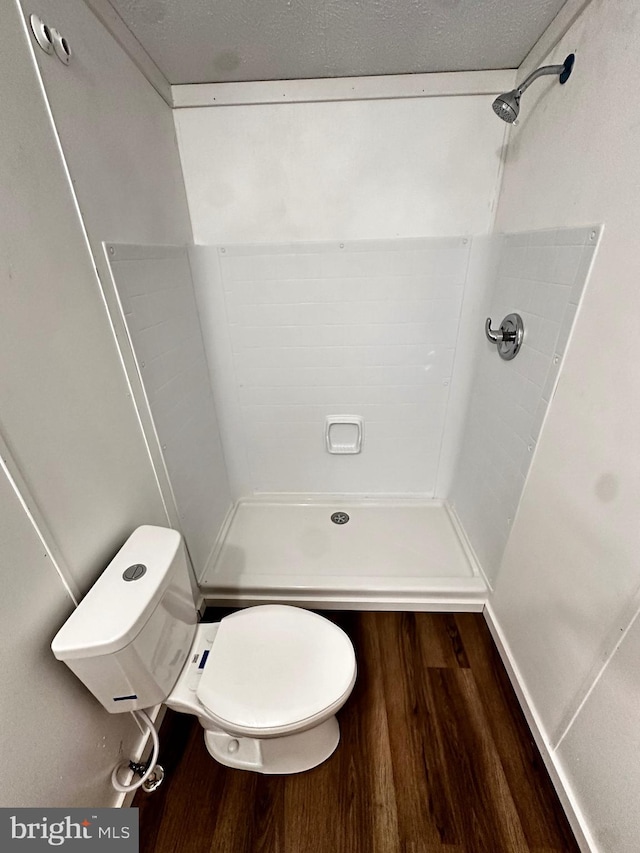 bathroom featuring hardwood / wood-style floors, toilet, walk in shower, and a textured ceiling