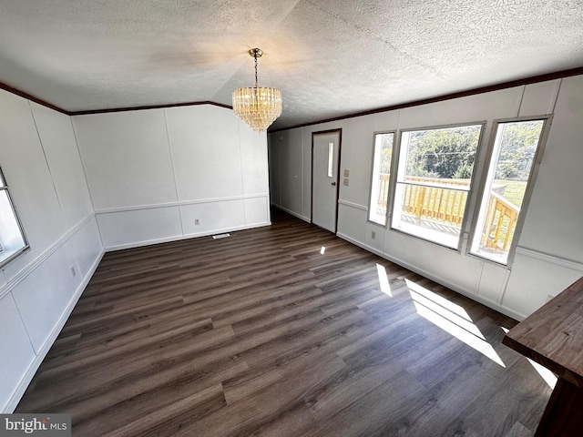 interior space with a notable chandelier, ornamental molding, a textured ceiling, dark hardwood / wood-style flooring, and lofted ceiling