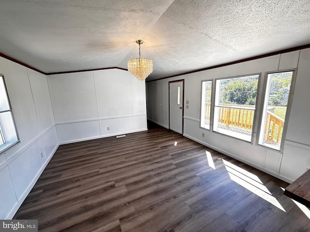 unfurnished room featuring a textured ceiling, vaulted ceiling, an inviting chandelier, dark hardwood / wood-style flooring, and crown molding