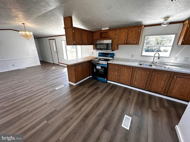 kitchen with a textured ceiling, plenty of natural light, electric range, and decorative light fixtures