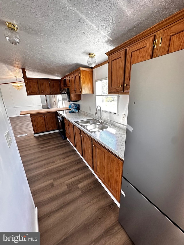 kitchen featuring dark hardwood / wood-style floors, stainless steel refrigerator, sink, and a textured ceiling