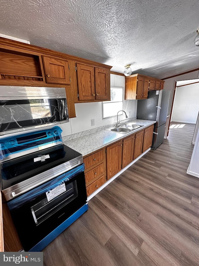 kitchen featuring a textured ceiling, stainless steel appliances, dark hardwood / wood-style flooring, light stone counters, and sink