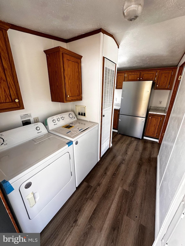 clothes washing area with a textured ceiling, dark wood-type flooring, ornamental molding, and washing machine and dryer