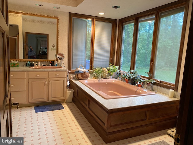 bathroom with a bathtub, vanity, a wealth of natural light, and a textured ceiling