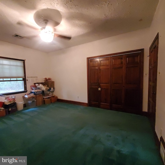 interior space featuring ceiling fan, carpet, and a textured ceiling