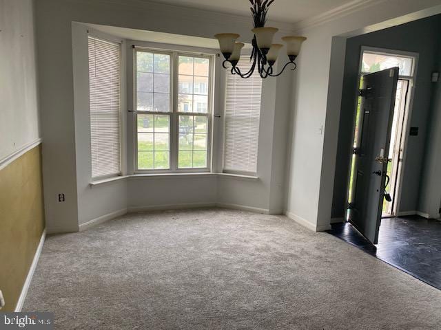 carpeted spare room featuring an inviting chandelier and ornamental molding