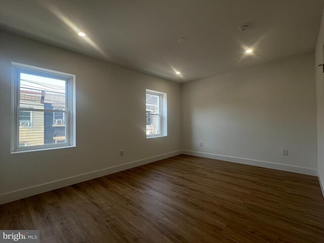 spare room with plenty of natural light and dark wood-type flooring