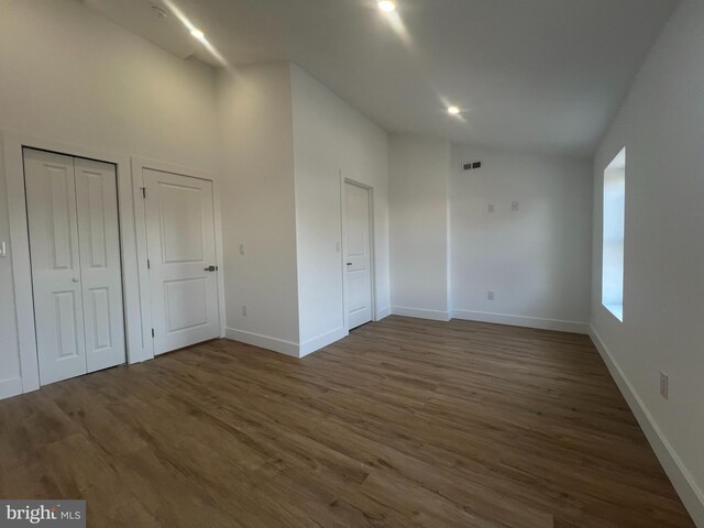 unfurnished bedroom featuring multiple closets and dark hardwood / wood-style flooring