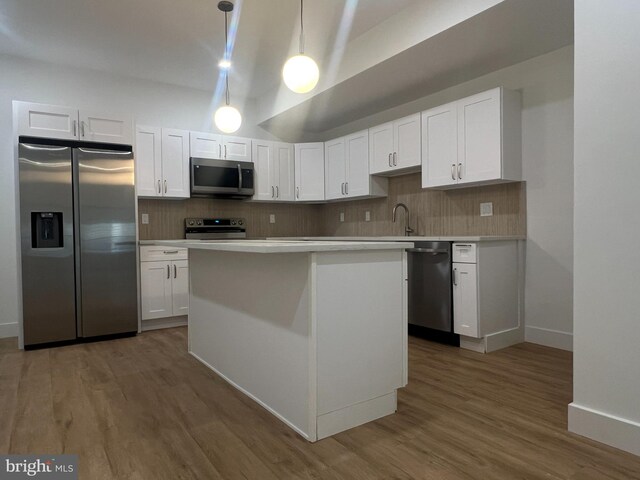 kitchen with appliances with stainless steel finishes, hanging light fixtures, white cabinetry, and dark hardwood / wood-style flooring