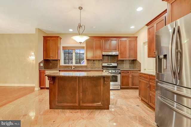 kitchen featuring sink, decorative light fixtures, stainless steel appliances, a center island, and light stone countertops