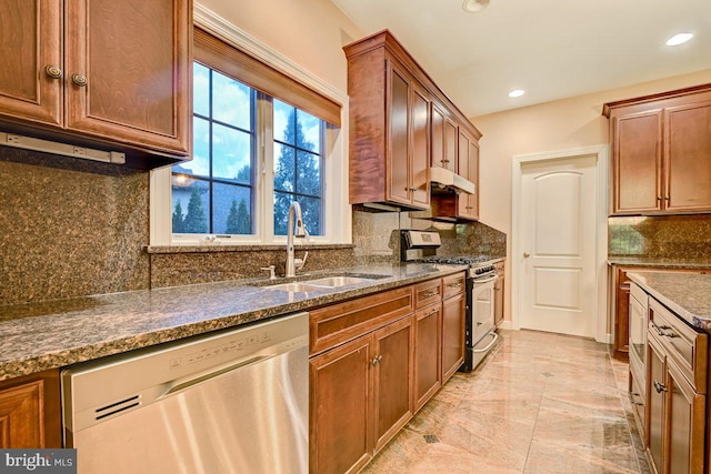 kitchen with appliances with stainless steel finishes, backsplash, dark stone countertops, and sink