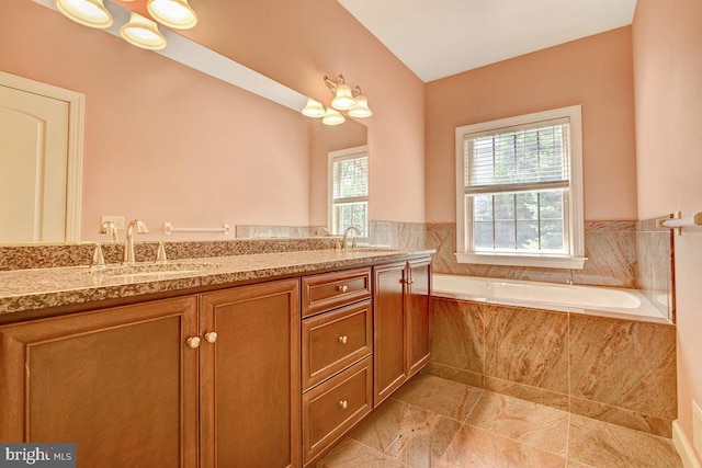 bathroom with tiled tub and vanity