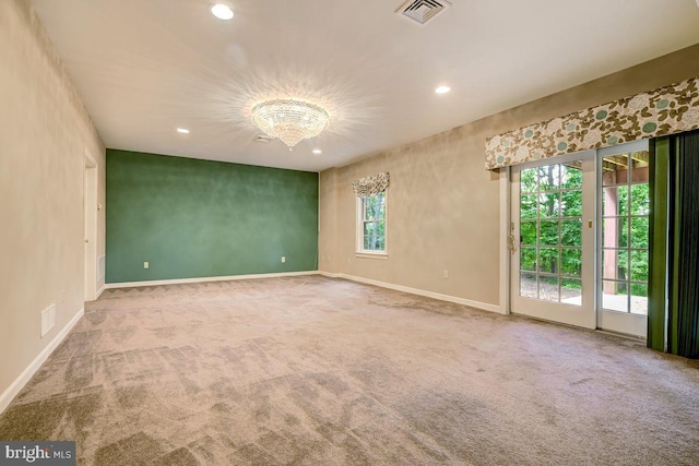 carpeted empty room featuring a notable chandelier