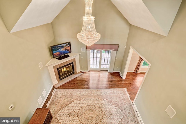 living room with wood-type flooring, a chandelier, a high end fireplace, and high vaulted ceiling